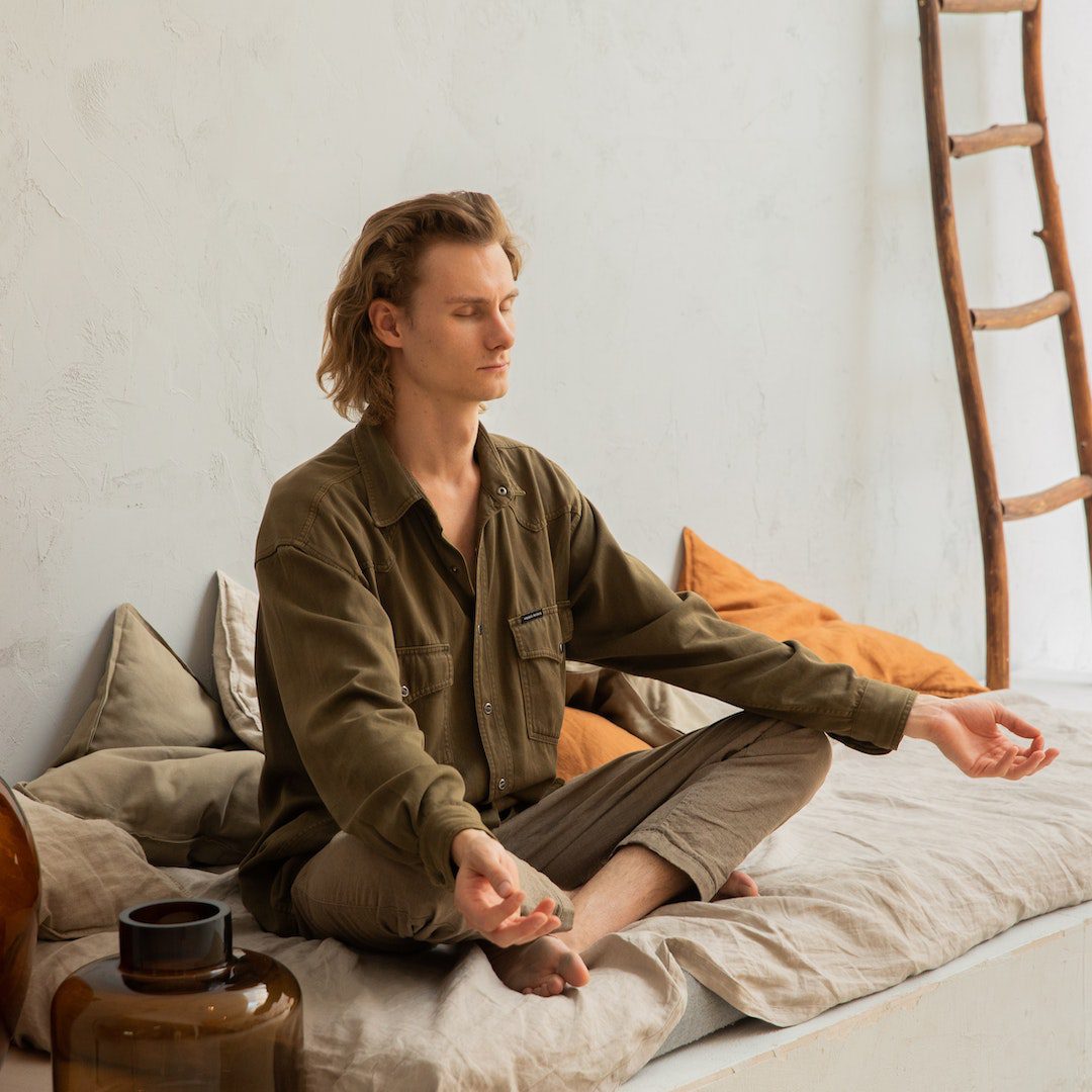 Concentrated man meditating in Lotus pose on mattress<br />
